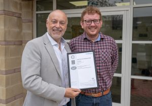 andrew scott and alex tremlett holding the ISO 9001 certificate
